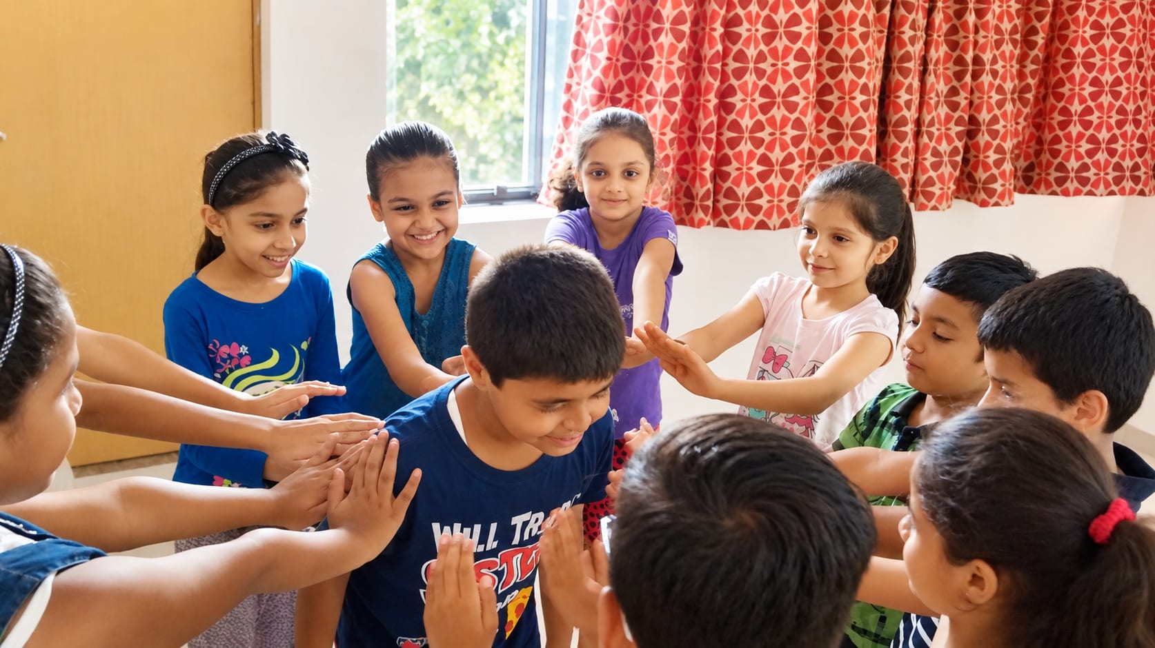 Children standing in a circle with their hands together during a session at Jatan